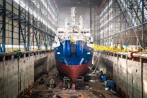 A vessel under construction in a covered shipyard dry dock